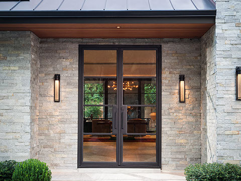 Custom glass and metal modern entry door at stone foyer